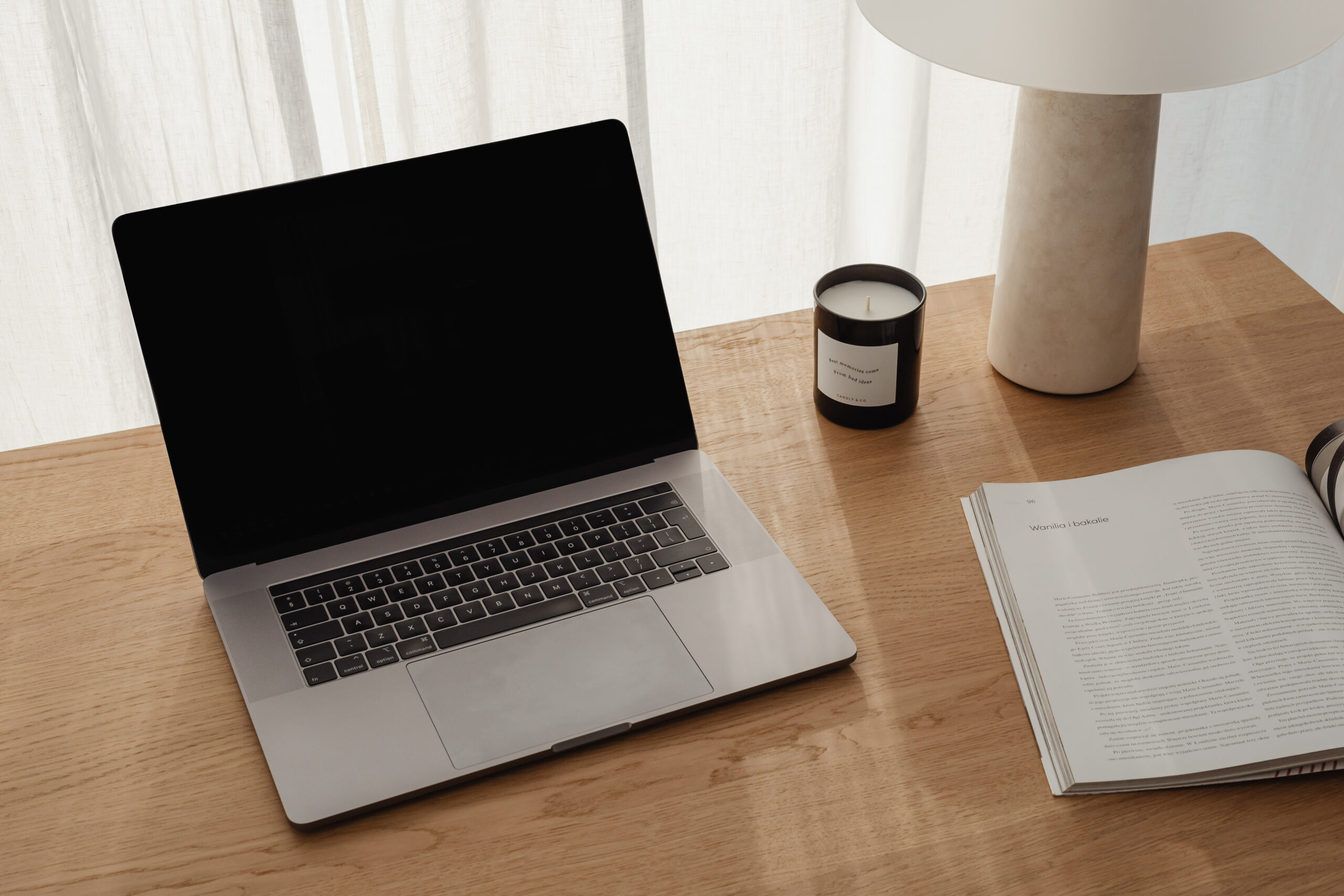 Laptop on a desk next to a candle in and aesthetic set up